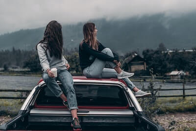 車の屋根に座る女性2人