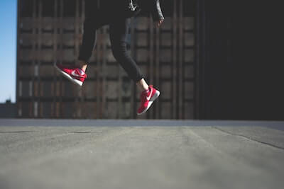 赤いスニーカーを履いて飛んでいる人の足元