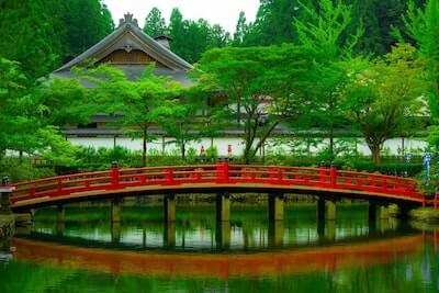池の水面に映る赤い橋と新緑の風景