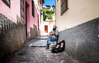 路地でギターを弾く男性