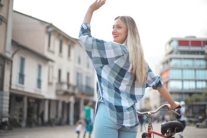 自転車を押しながら手を振る女性