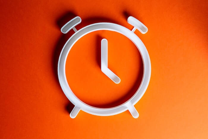 オレンジの背景に白い時計の輪郭