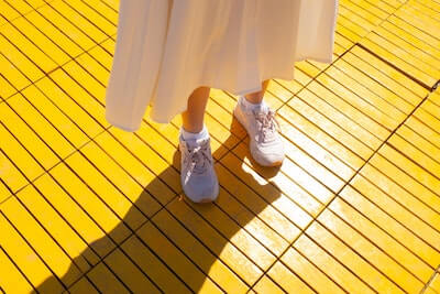 黄色い床に白いスニーカーの女性