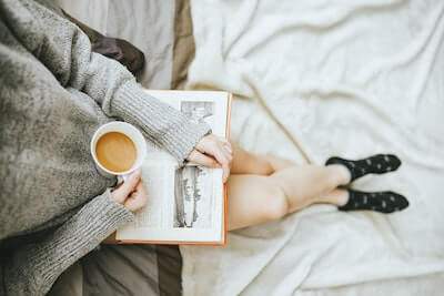 本を読みながらコーヒーを飲む女性